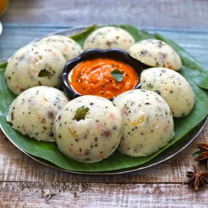 side shot of rava idli in a plate with tomato chutney