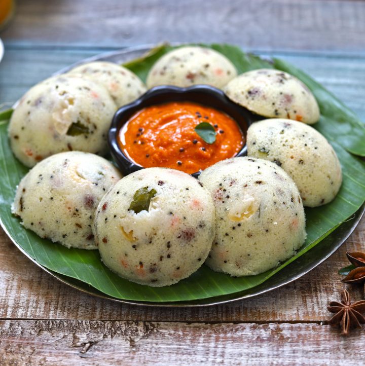 side shot of rava idli in a plate with tomato chutney