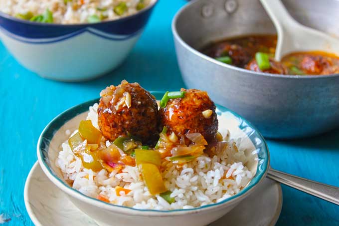 side shot of vegetable manchurian balls over fried rice in a white bowl