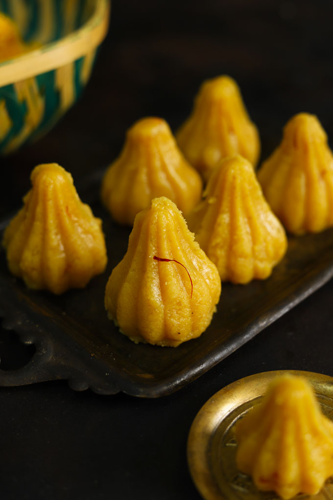 side shot of khoya modak arranged on a black serving tray