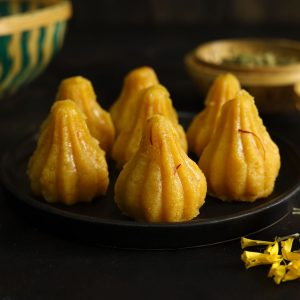 close up side shot of mawa modak on a black platter