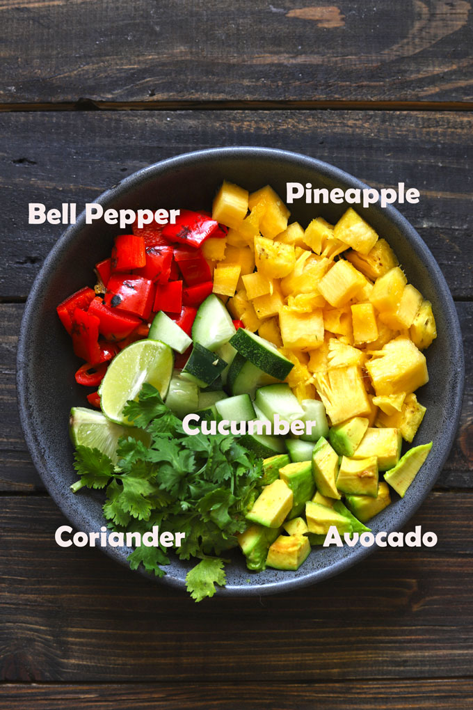 aerial shot of ingredients in a pineapple salsa in a black ceramic bowl.