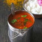 side shot of tomato garlic rasam in a stainless steel container