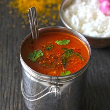 side shot of tomato garlic rasam in a stainless steel container