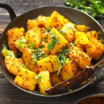 side close up shot of aloo gutuk in a cast iron skillet