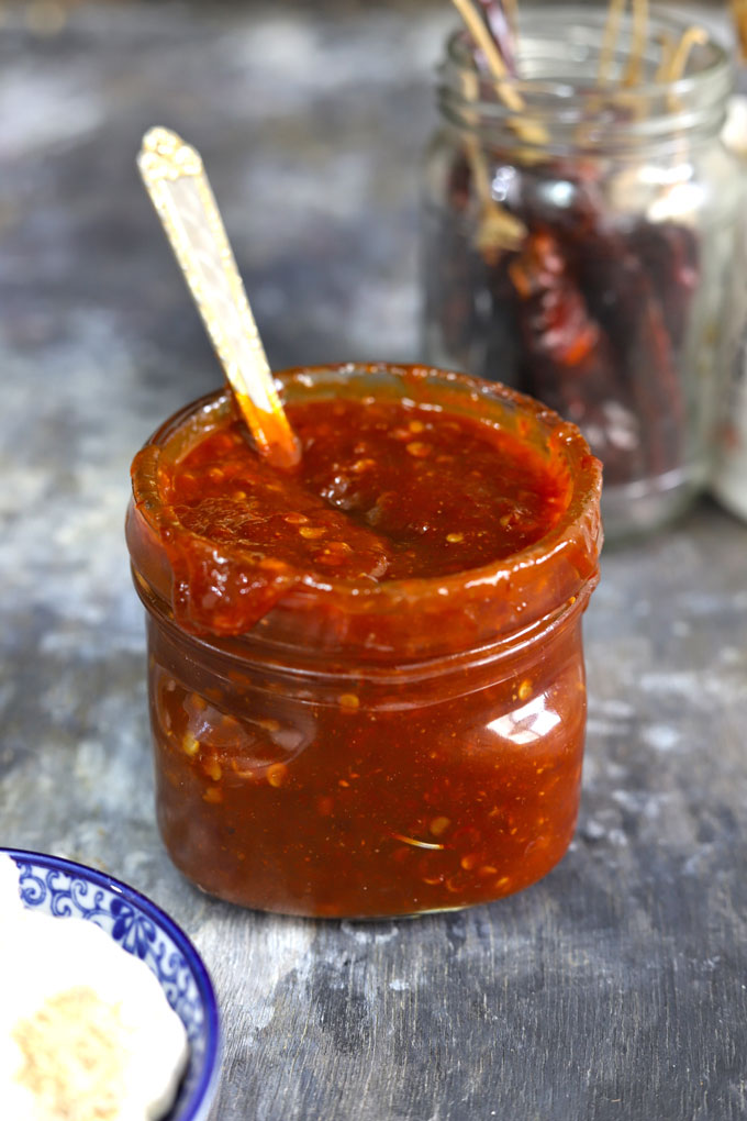 side shot of sweet chilli sauce in a glass bottle with a spoon