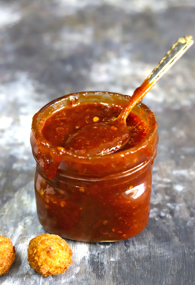 side shot of sweet chilli sauce in a glass bottle with a spoon