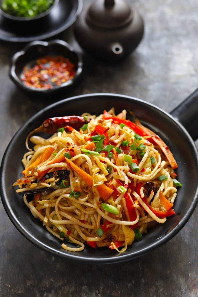 side close up shot of chilli garlic noodles in a black serving bowl