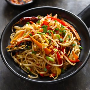 side close up shot of chilli garlic noodles in a black serving bowl