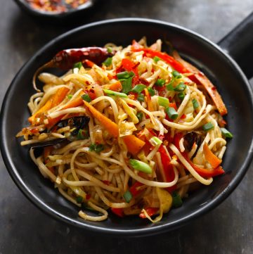 side close up shot of chilli garlic noodles in a black serving bowl