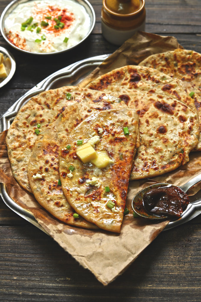 side close up shot of spring onion paratha stack with butter on top