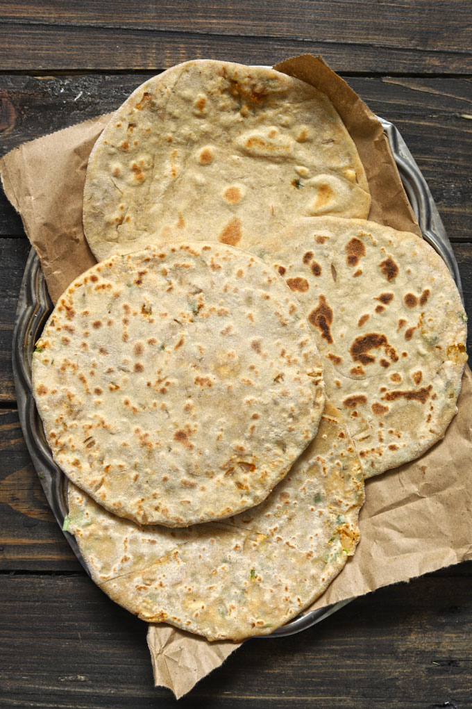 aerial shot of uncooked paneer paratha stacked on a steel platter