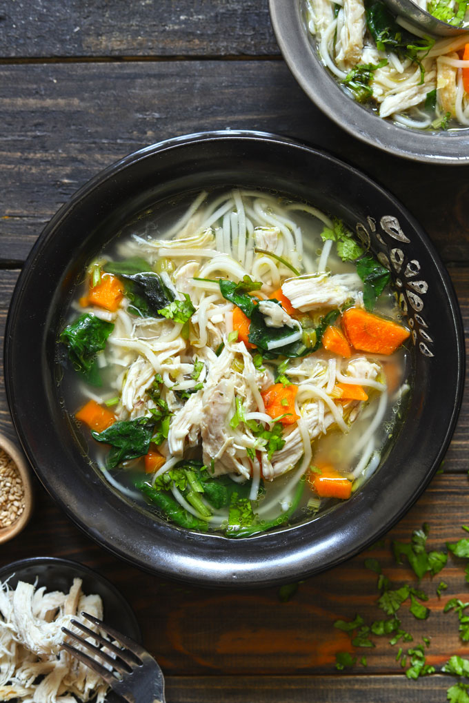 aerial shot of chicken noodle soup in a black ceramic bowl