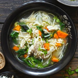 aerial shot of chicken noodle soup in a black bowl