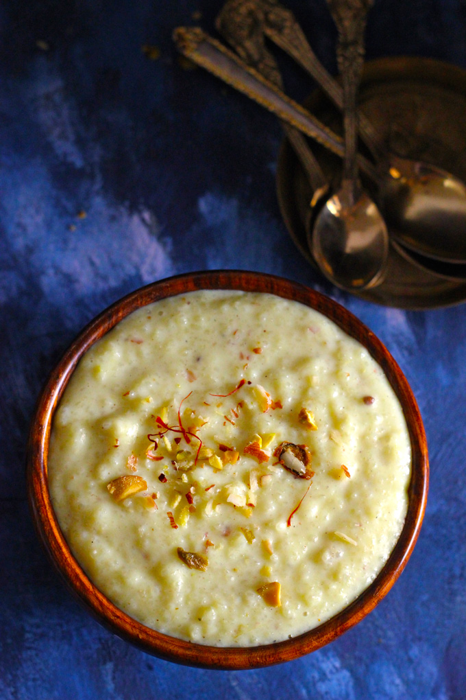 aerial shot of firni in a wooden bowl garnished with nuts and saffron