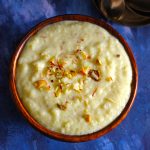 aerial shot of phirni in a wooden bowl garnished with nuts and saffron