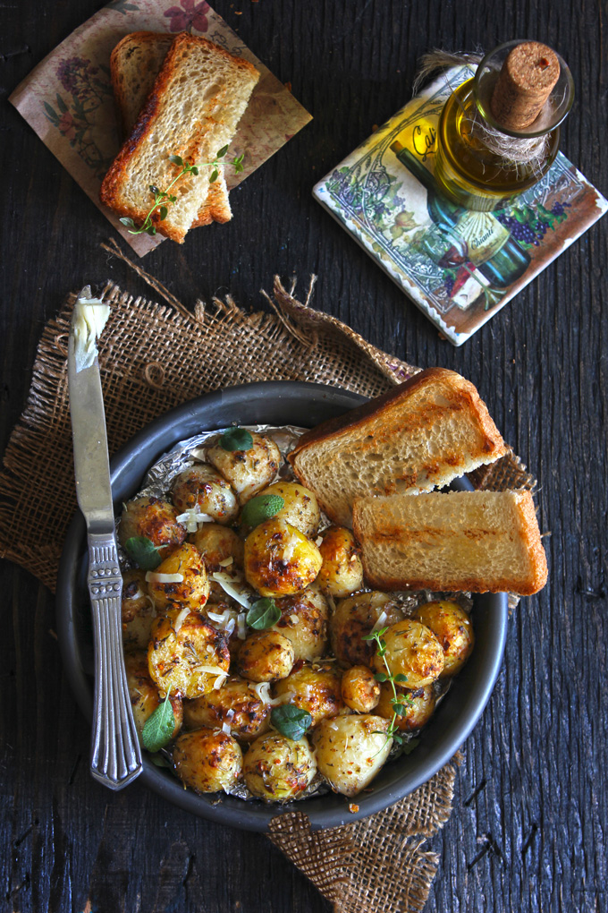 aerial shot of roasted potatoes in a black bowl with slices of bread