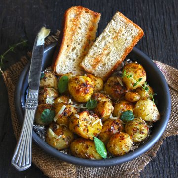 side close up shot of garlic roasted potatoes on a black bowl