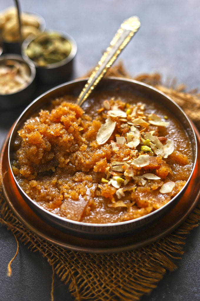 side close up shot of sooji halwa with spoon in a steel bowl