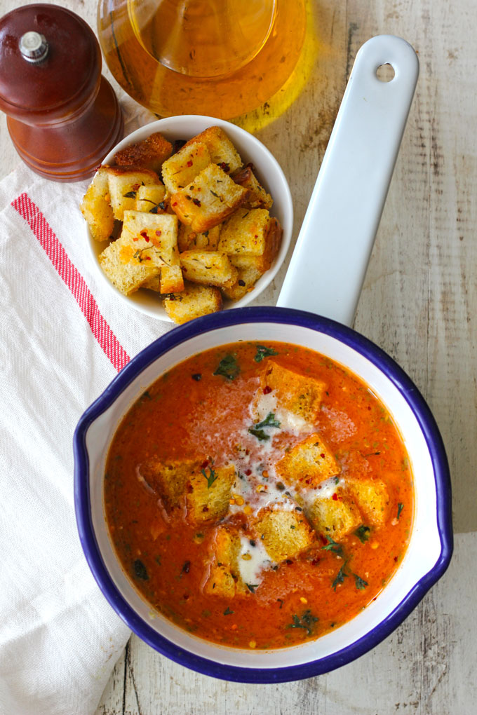 aerial shot of a tomato soup with bread croutons on a white saucepan