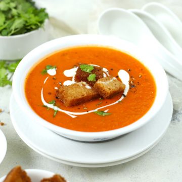 side close up shot of creamy tomato soup in a white serving bowl
