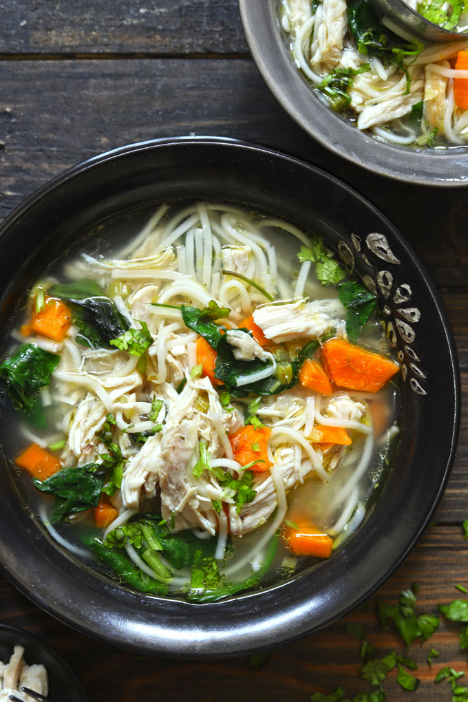 aerial shot of chicken noodle soup in a black ceramic bowl