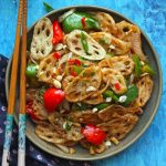 aerial shot of crispy lotus stem stir fry on a black platter with chopsticks on the side