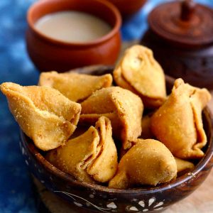 side close up shot of moong dal samosa stacked on a wooden bowl