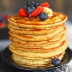 side close up shot of whole wheat pancakes stacked topped with fresh berries