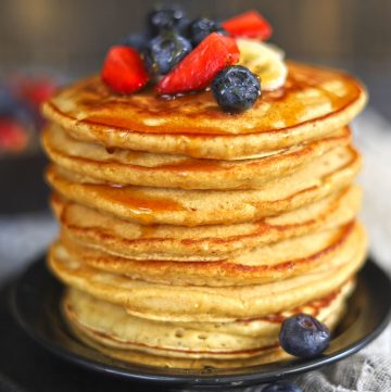 side close up shot of whole wheat pancakes stacked topped with fresh berries