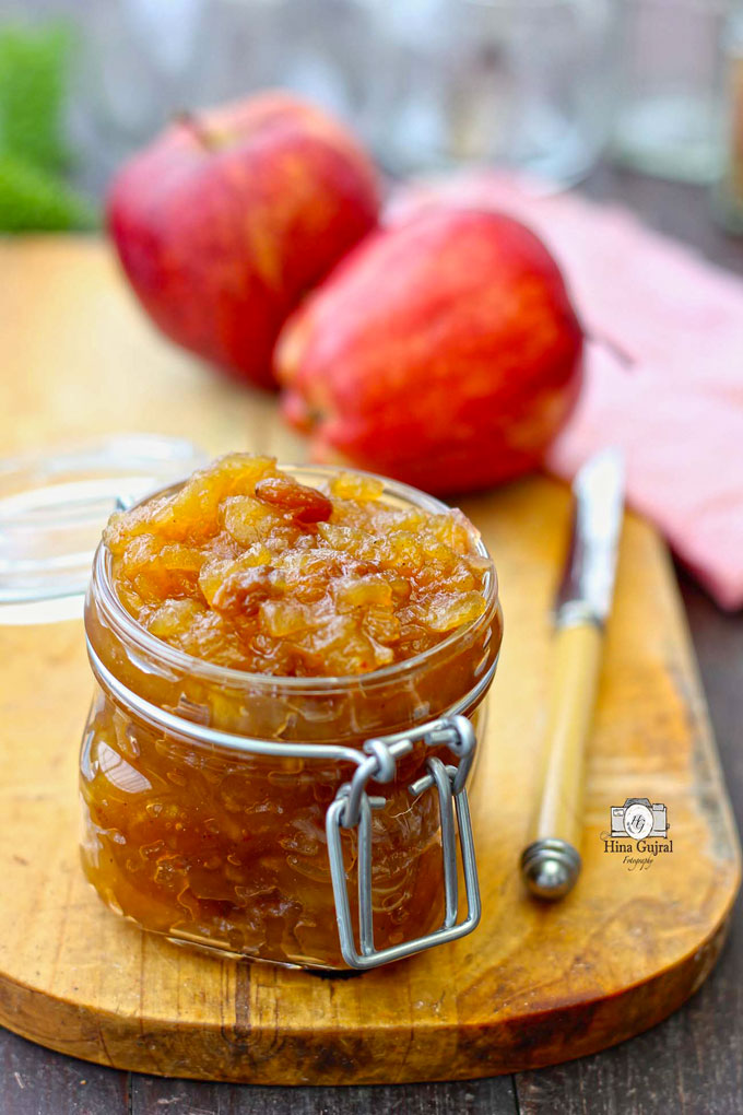 side shot of savory apple raisin chutney in a glass jar with a spoon