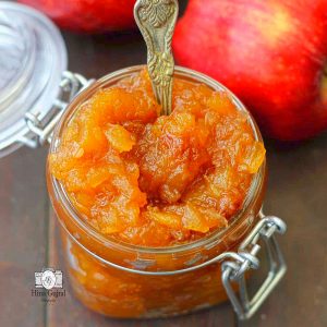 side shot of savory apple chutney in a glass jar with a spoon