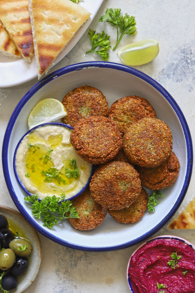 aerial shot of chickpea falafel stacked on a white plate with hummus