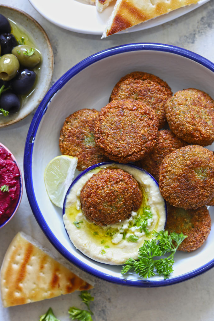 aerial shot of chickpea falafel stacked on a white plate with hummus