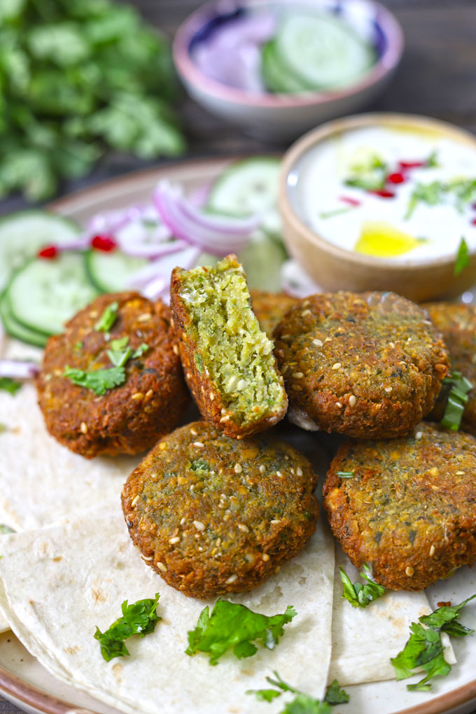 side close up shot of falafel stacked on a platter with a dip