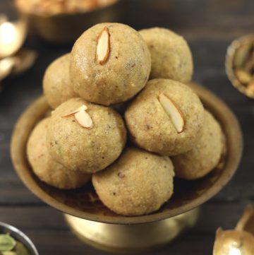 side shot of atta ladoo stacked on a golden platter