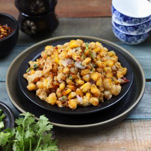 side shot of crispy corn stacked on a black plate