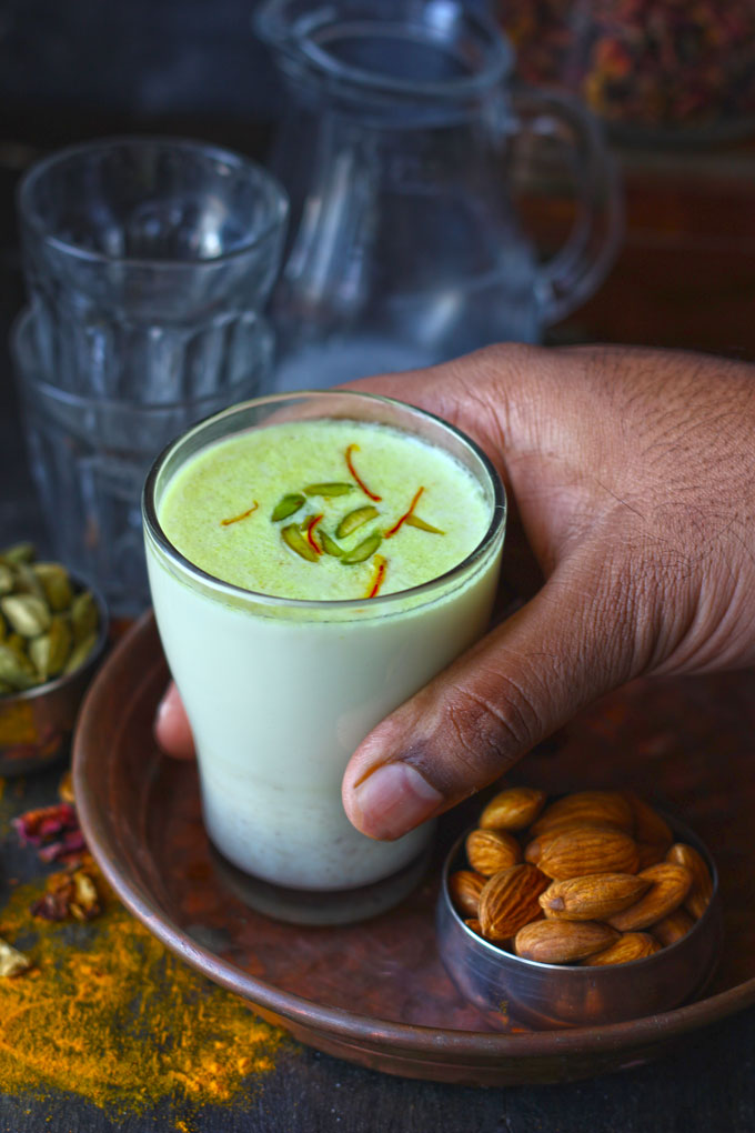 side shot of khas khas doodh in a glass with a hand holding it.