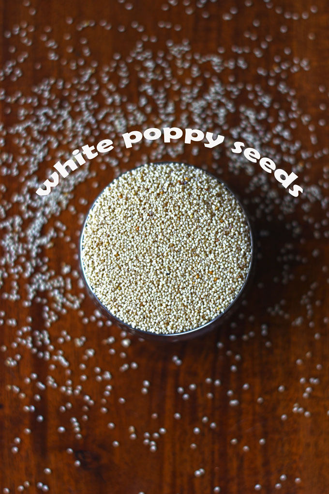 aerial shot of white poppy seeds in a steel bowl on a wooden surface