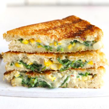 side shot of grilled spinach corn sandwich stacked on a white board