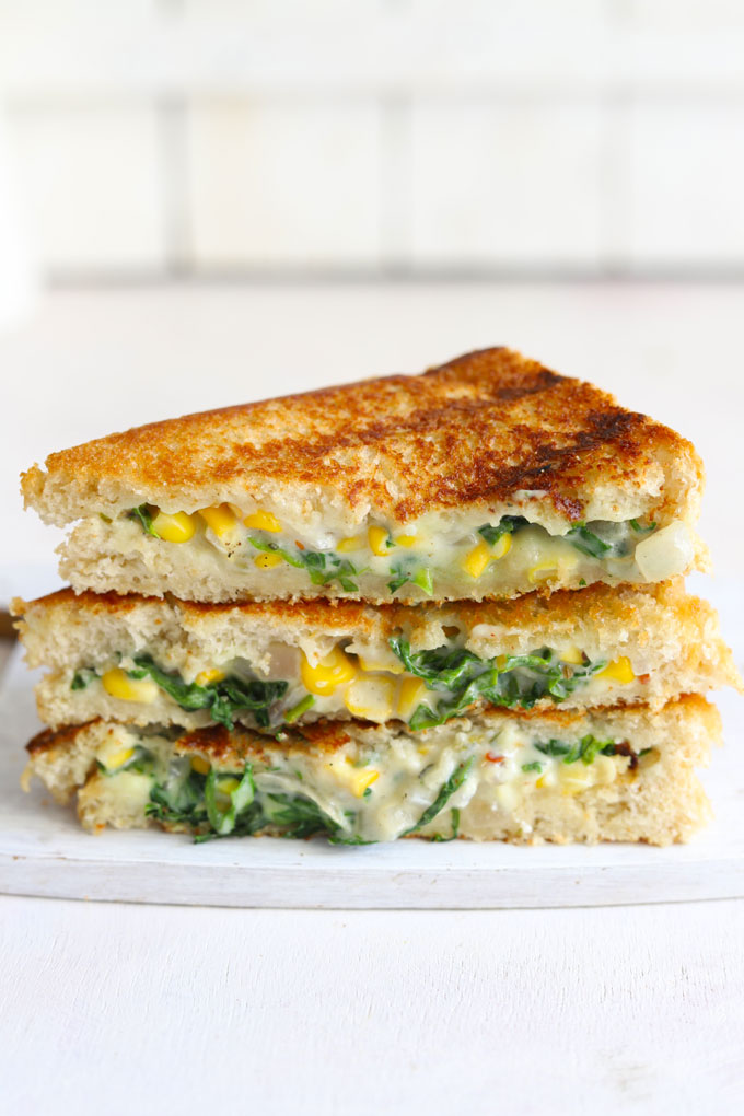 side shot of grilled spinach corn sandwich stacked on a white board