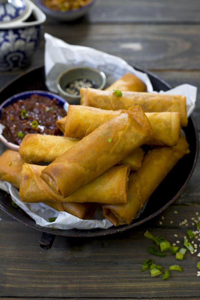 side shot of spring roll stacked on a black platter