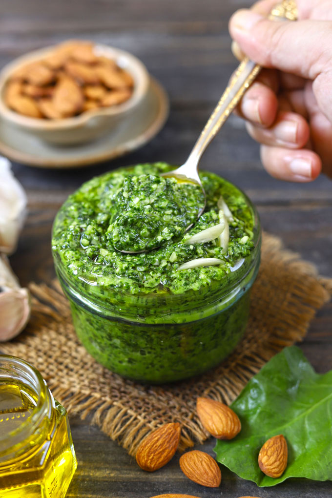 side close up shot of spinach almond pesto sauce in a glass jar
