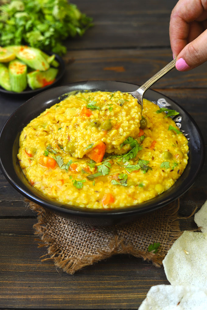 side close up shot of dalia khichdi in a black bowl with serving spoon
