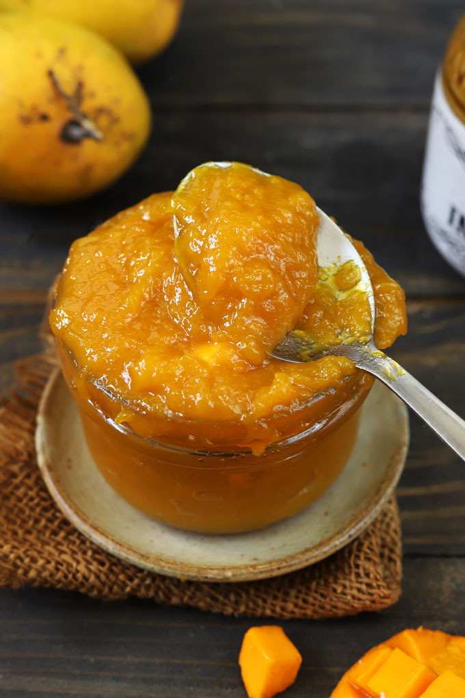 side shot of mango jam with a spoon in a jar