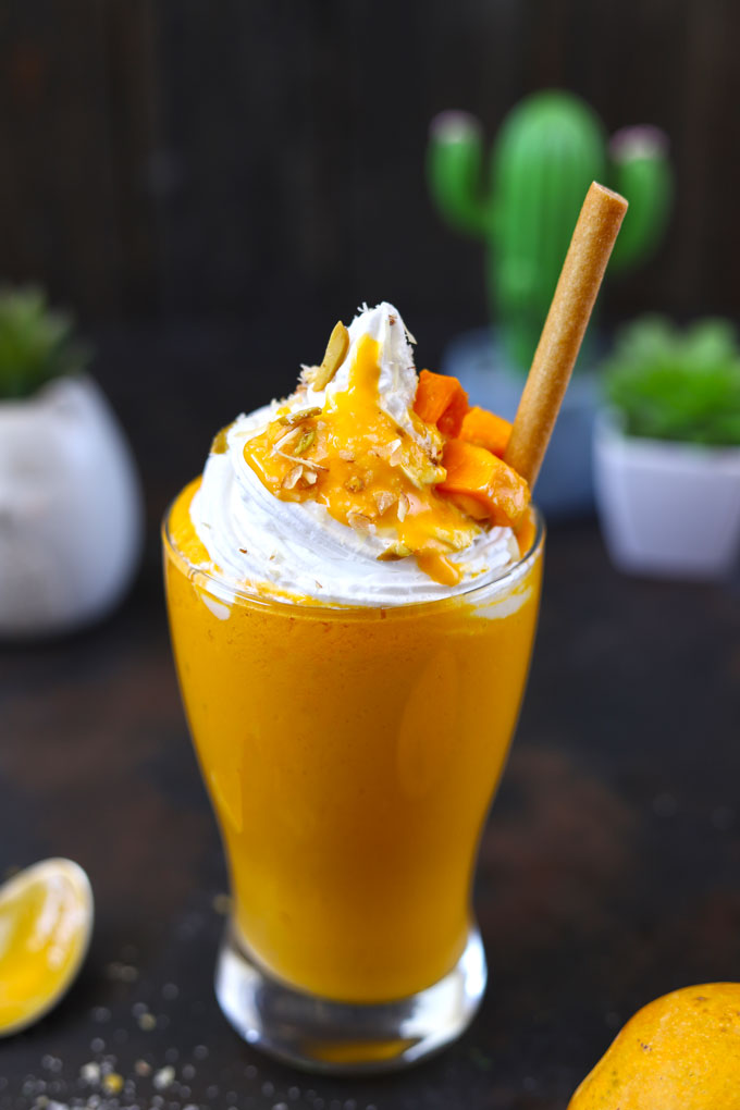 side shot of mango shake in a glass with edible straw