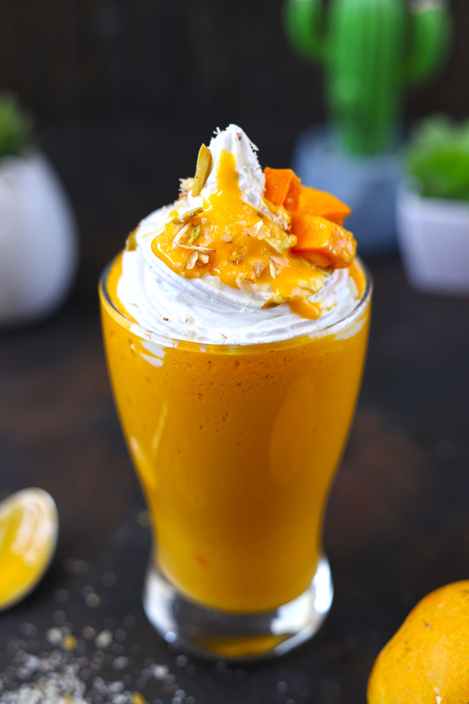 side shot of mango milkshake in a glass with edible straw