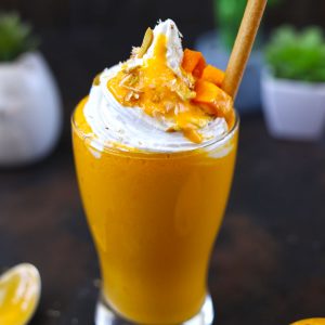 side shot of mango shake in a glass with edible straw