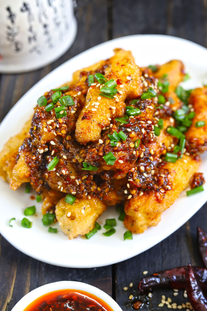 side shot of chili baby corn stacked on a oval white platter