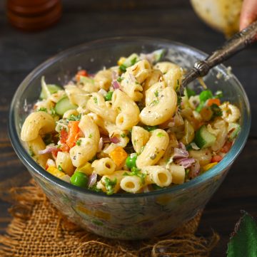 side shot of pasta salad in a bowl with a serving spoon